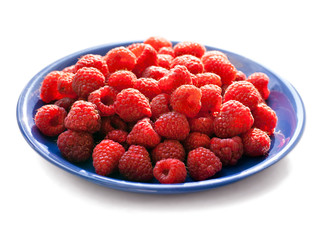 lots of ripe raspberries on the blue plate