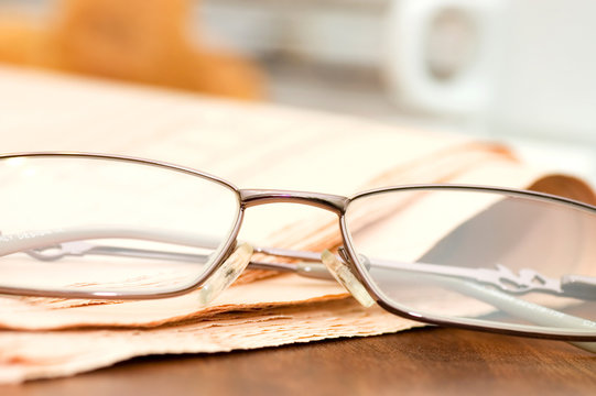 Eyeglasses on the newspaper on a wooden table