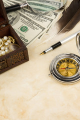 pen, magnifier, feather and compass near dollars