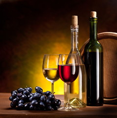 Still life with wine bottles, glasses and oak barrels.