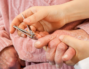 Helping senior woman cutting her nails