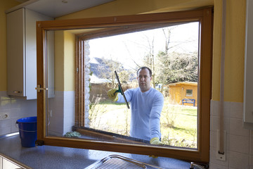 Mann beim Fenster putzen