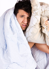 A tired looking man in bed. He is holding a pillow