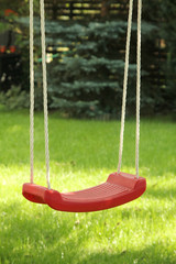 Red garden swing hanging in garden