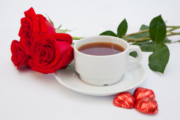 bouquet of red roses next to a cup of tea