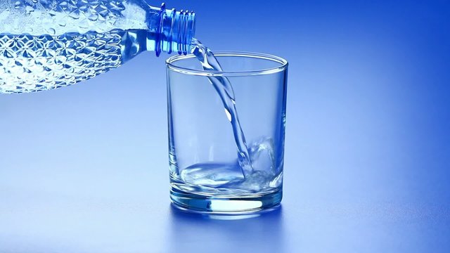 Hand plastic bottle of water and pouring into empty glass