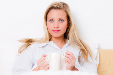 junge frau trinkt tee im bett