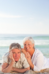 Fototapeta na wymiar Elderly couple lying down on the beach
