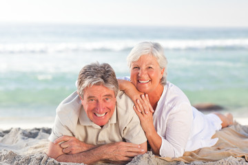 Elderly couple lying down on the beach