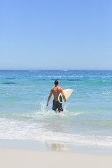 Fototapeta na wymiar Man running on the beach with his surfboard