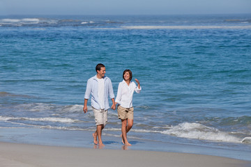 Fototapeta na wymiar Couple walking on the beach under the sun