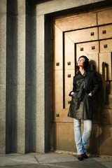 Beautiful young woman near the bronze doors