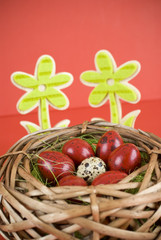 Easter eggs in wicker basket on red background