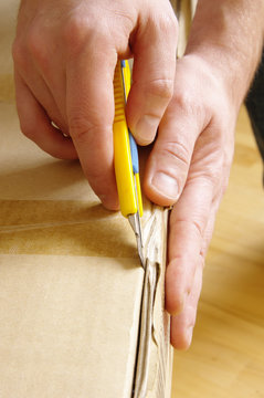 Men unpacking box with cutter