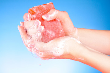 Hands with soap on blue background