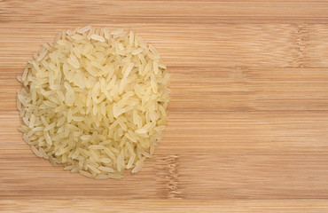 Pile of raw rice on wooden table, view from top, space for text