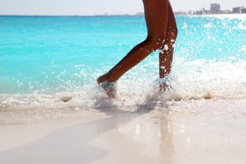 Woman legs walking splashing beach aqua water