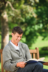 Young man reading his book on the bench