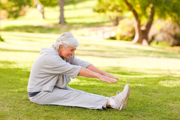 Naklejka na ściany i meble Retired woman doing her stretches in the park