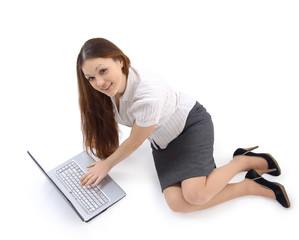 Smiling girl works with the laptop lying on the floor