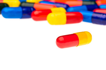 One red yellow capsule in front of many colorful