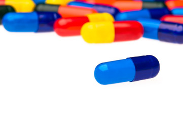 One blue capsule in front of many colorful