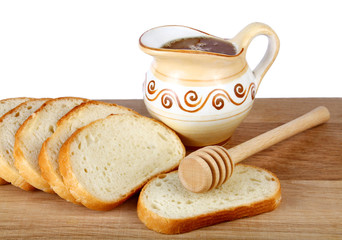 honey in a jug and loaf on board