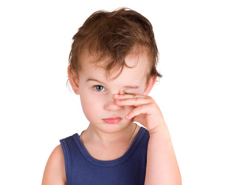 A tired little boy rubbing eyes, isolated on white