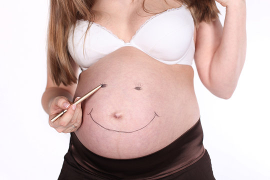 Pregnant belly and a hand painting the smile