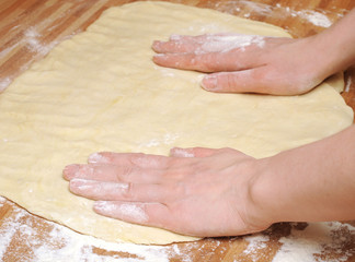 Preparing pizza dough in a kitchen.