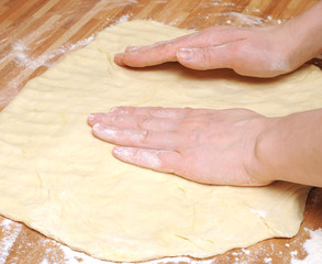 Preparing pizza dough in a kitchen.