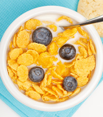 bowl of cornflakes with milk and blueberries