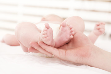 parental hand holds legs of the baby