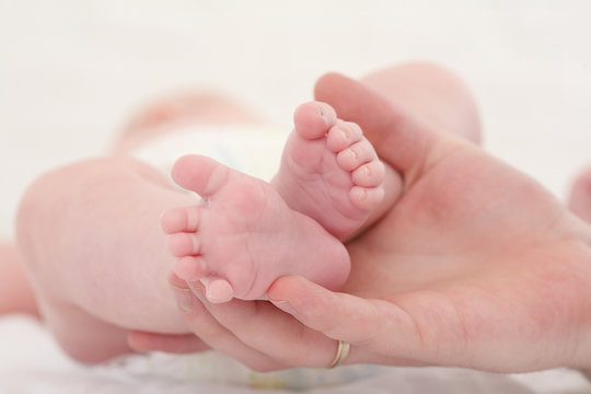 parental hand holds legs of the baby