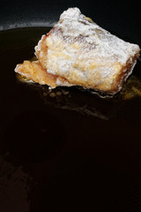 Piece of breaded in flour and eggs fish on frying pan