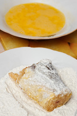 breaded fish in plate with flour and blurred mixed egg yolk