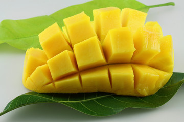 quartier de mangue découpé en dés sur feuilles de manguier