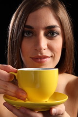 Beautiful woman holding yellow tea cup and saucer