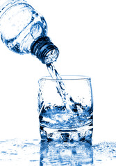 Water splashing from bottle into glass isolated on white