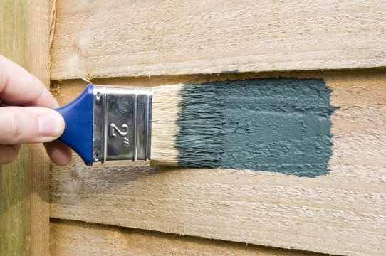 Green Wood Stain Being Painted Onto A Fence