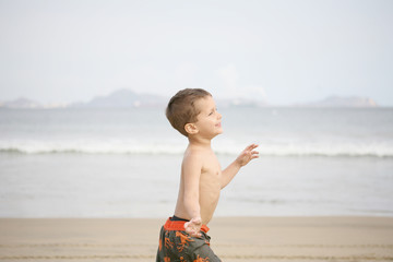 young boy playing on the beach and waves