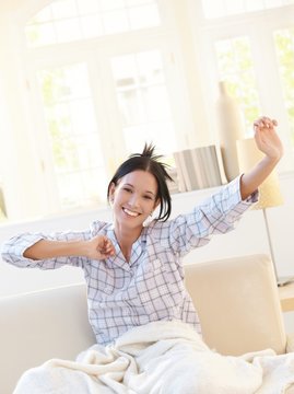 Happy attractive woman stretching in pyjama