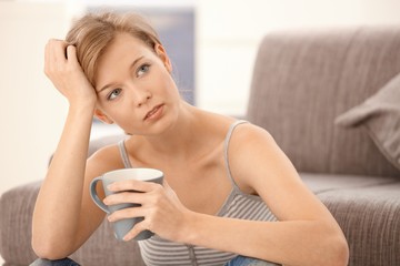 Young woman thinking with tea in hand