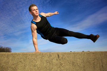Young man jumping over wall on obstacle course - Powered by Adobe