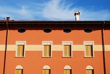 New decorated orange house detail on blue sky, Italy