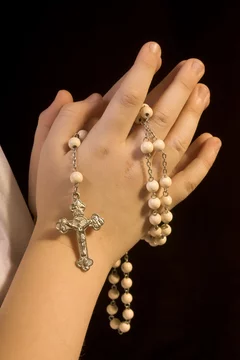 Mädchen betet Rosenkranz mit Kreuz mit Jesus an Kommunion in Ki Stock Photo
