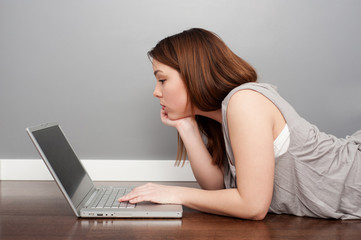 woman with laptop lying on floor