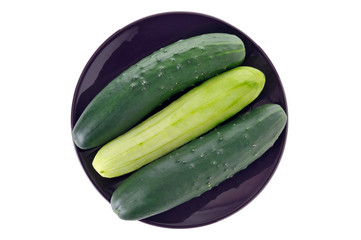three whole cucumbers in a dish, one peeled