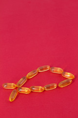 Capsules of Healthy, Golden Fish Oil on Red