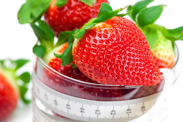 big juicy red ripe strawberries in a glass bowl and measure tape